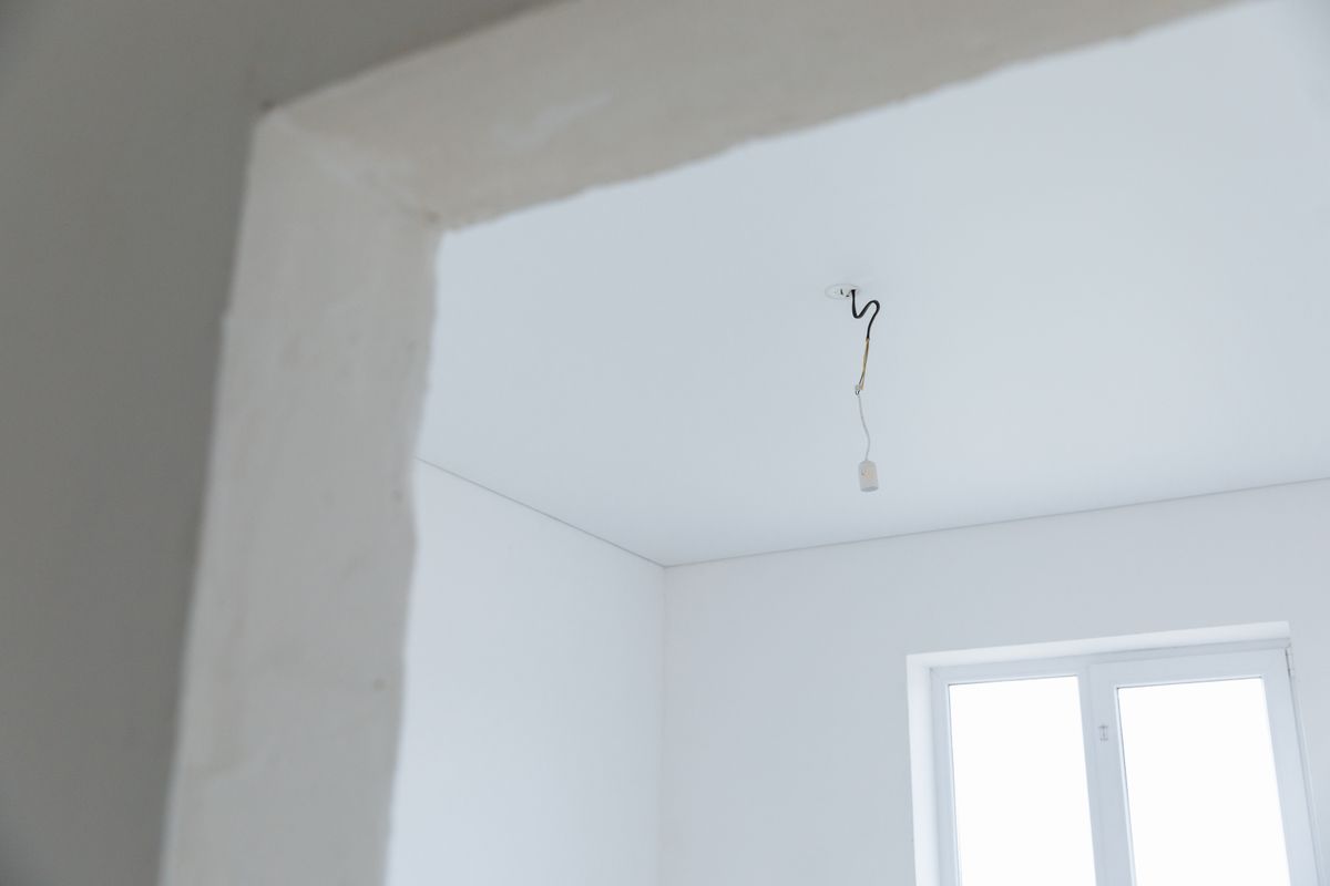 Unfinished white ceiling with a hanging electrical cable