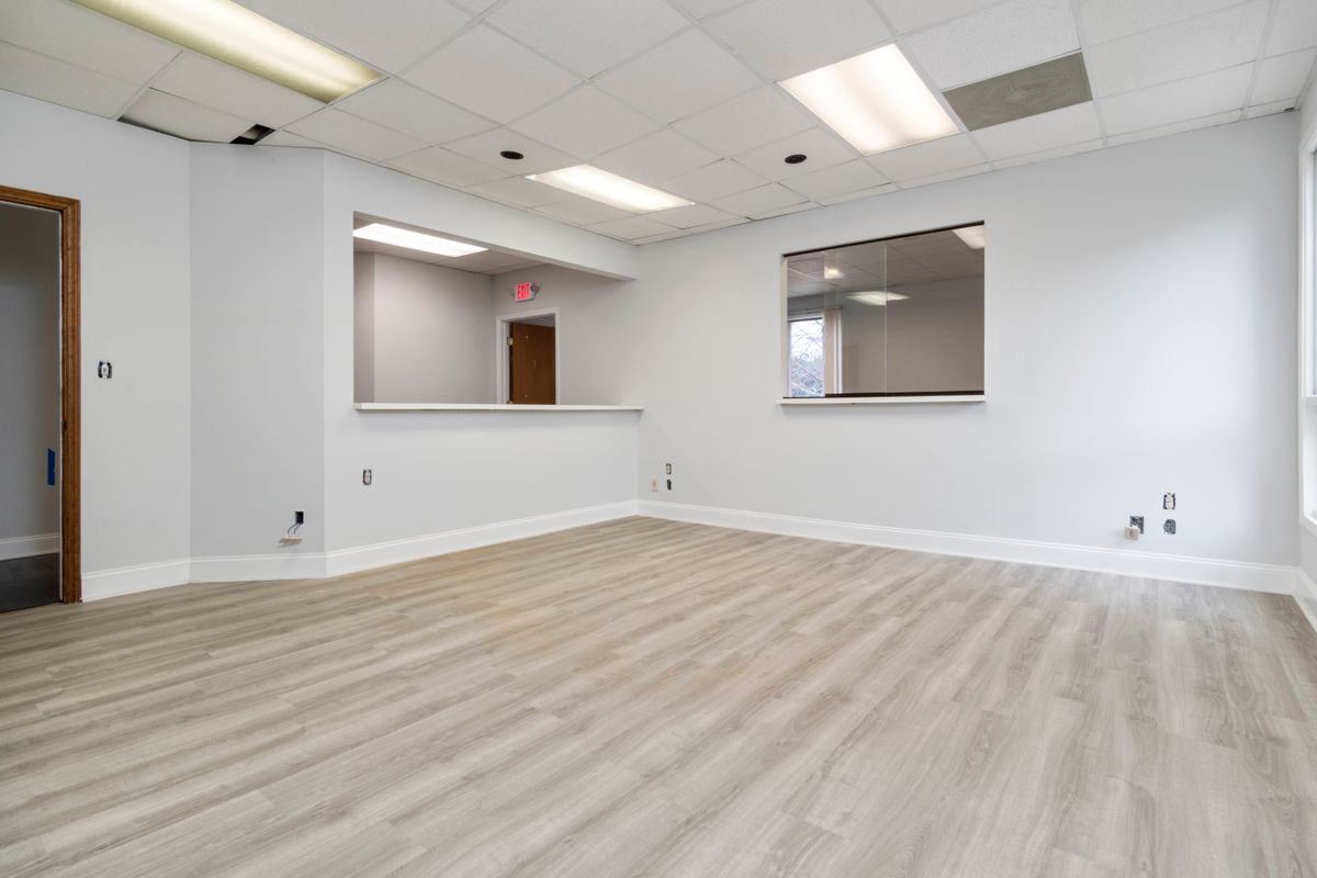 Empty room with wood-toned flooring and pale walls