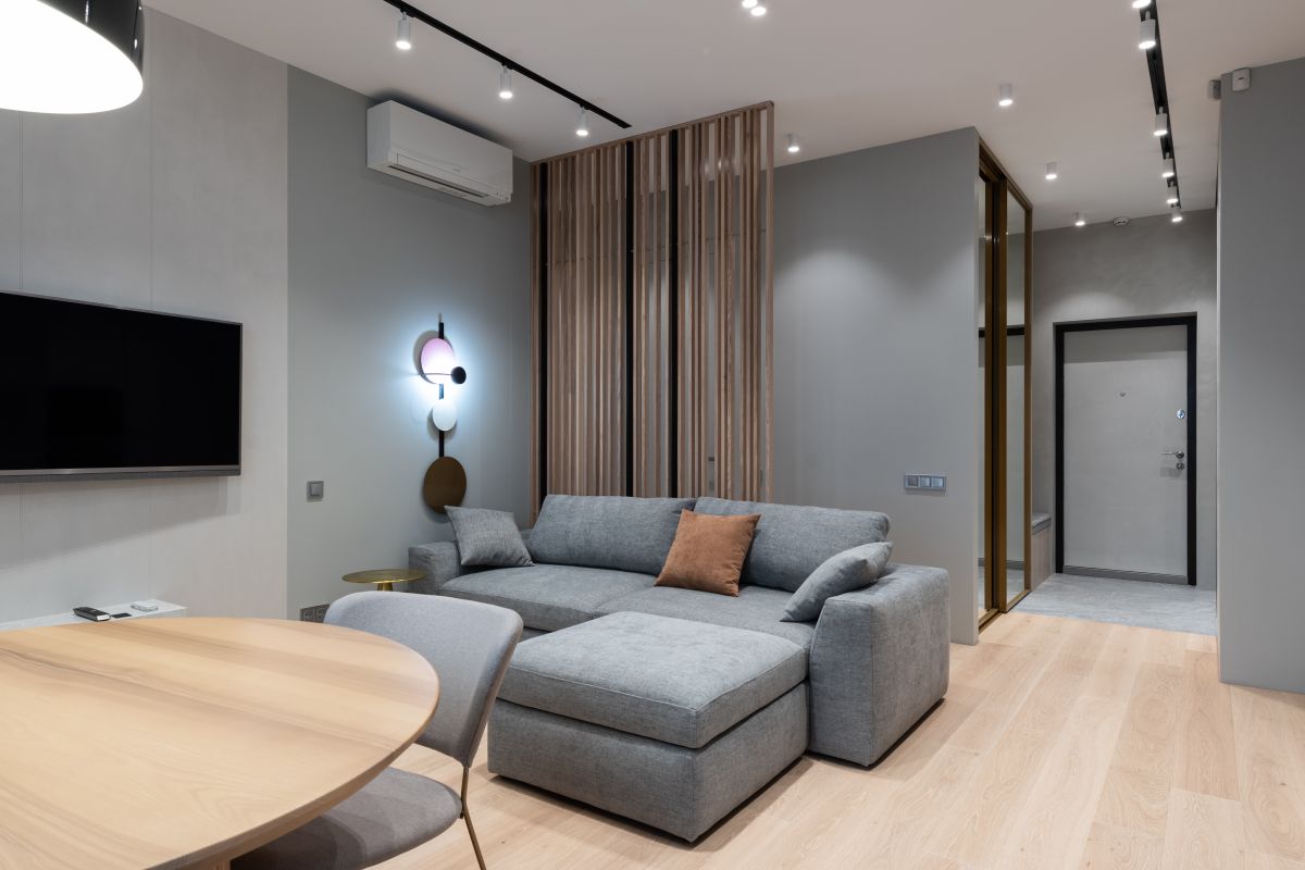 Grey sofa and dining table in a living room with timber screening