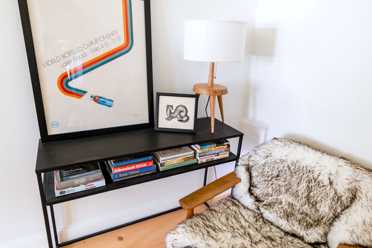 Wooden armchair with a textured throw beside a bookshelf and table lamp
