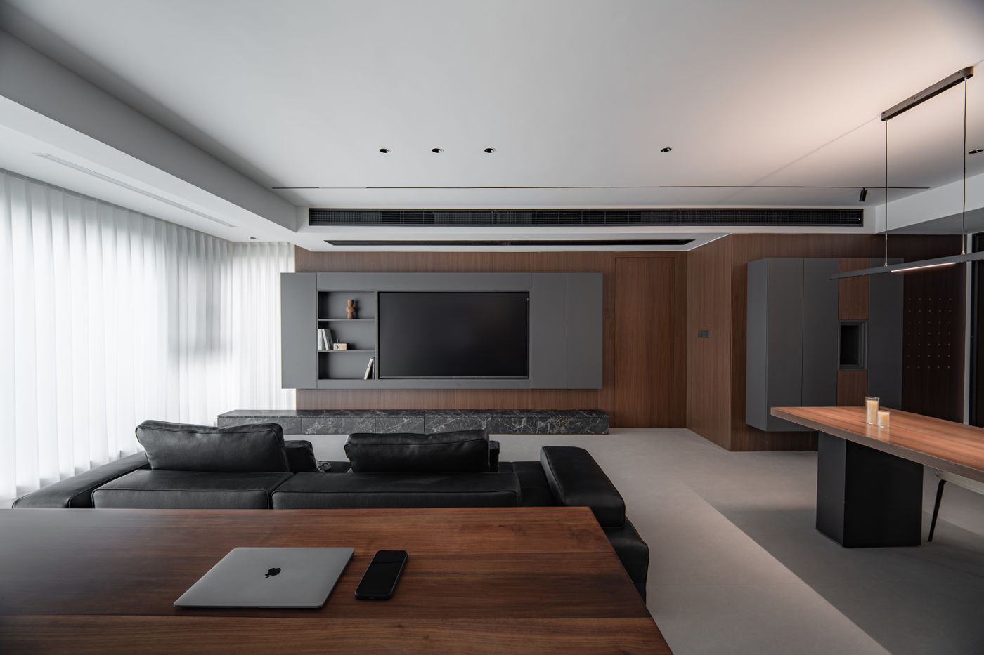 Laptop on a wooden work surface behind a sofa in a shared living area