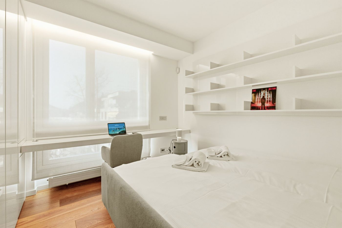 Bedroom with a desk and chair beside the window, alongside the bed